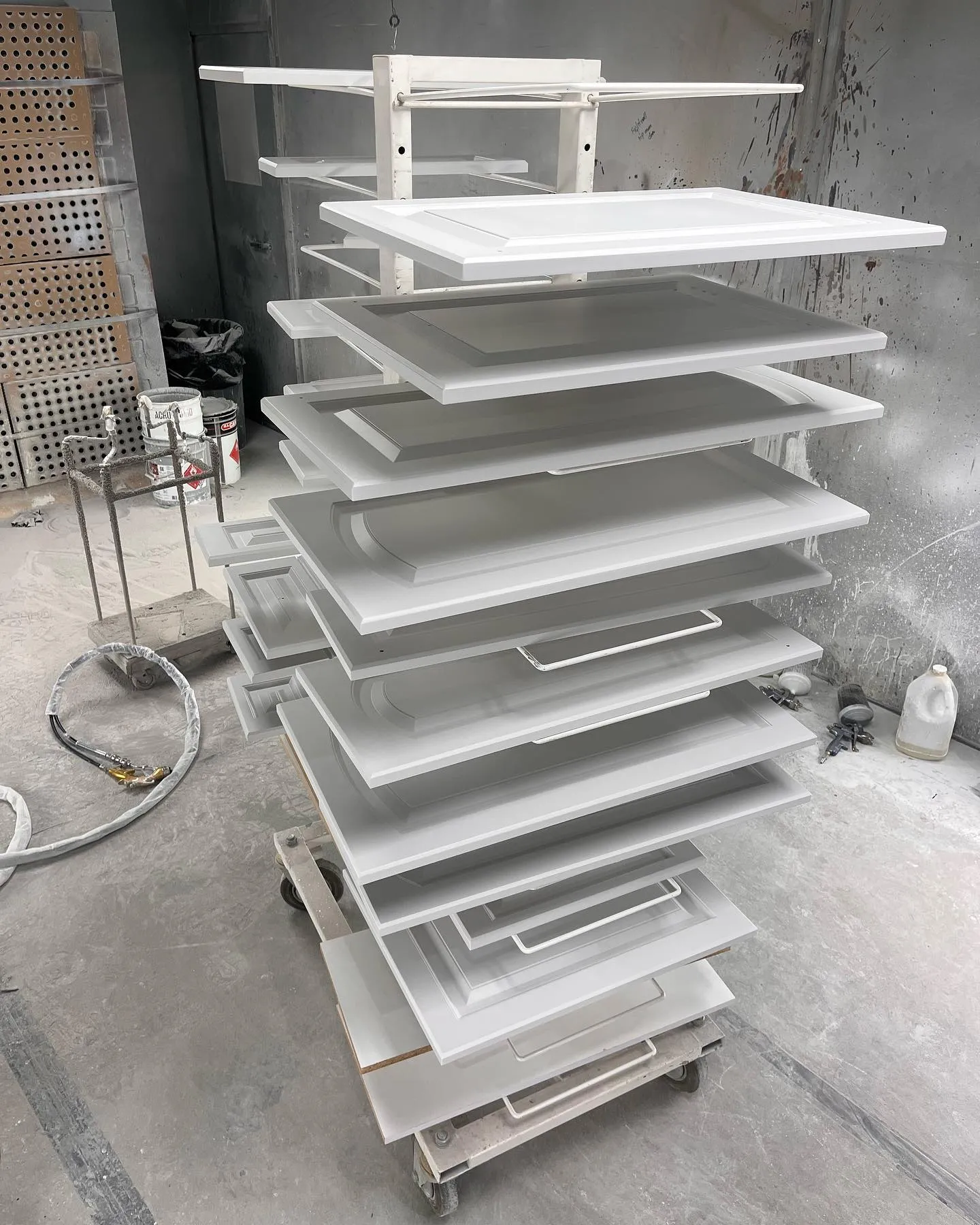 Sprayed cabinet doors curing on drying racks in the shop spray booth, Calgary