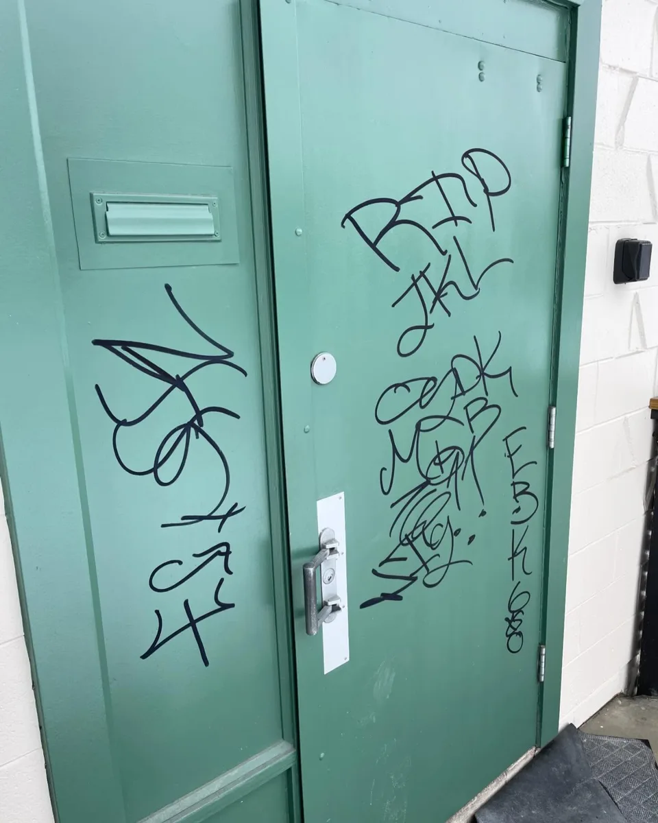 Commercial metal door covered in graffiti before repainting (Calgary Tennis Club)
