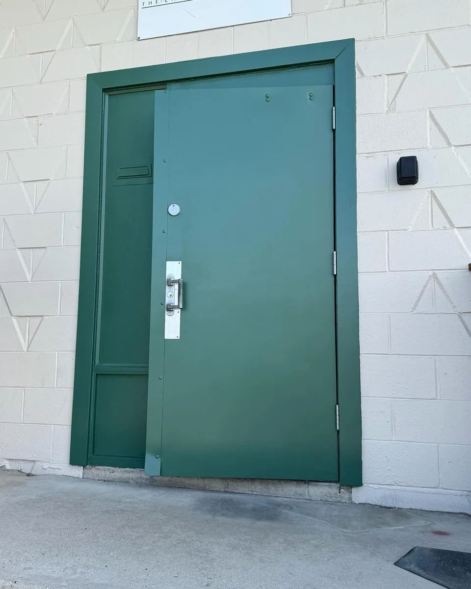 Commercial metal door repainted green after graffiti removal, Calgary
