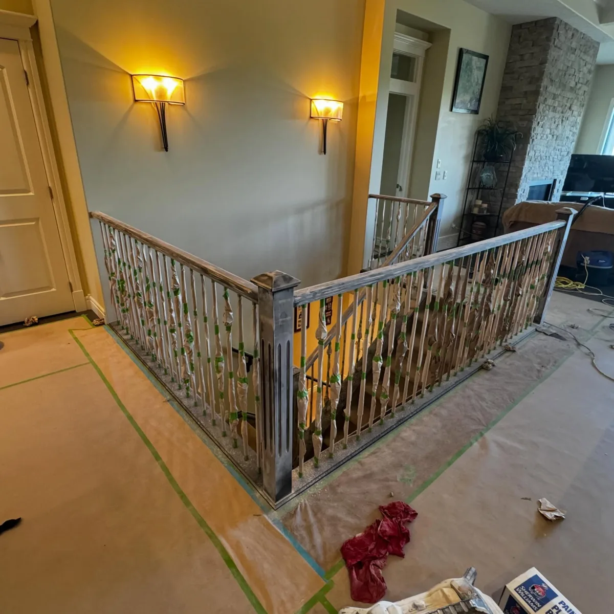 Staircase railing with spindles masked and taped for refinishing, Calgary
