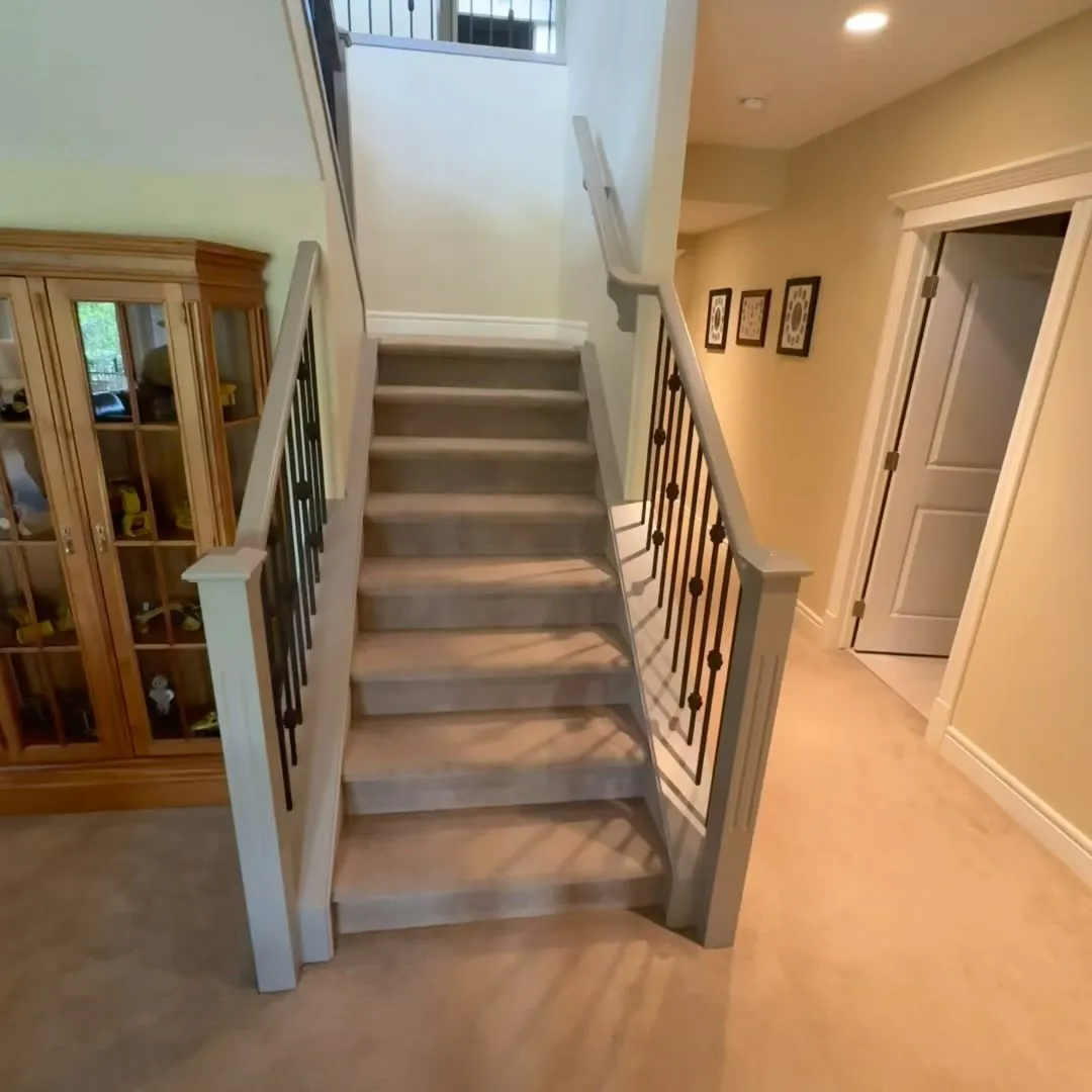 Finished staircase with dark metal spindles and white newel posts in Calgary