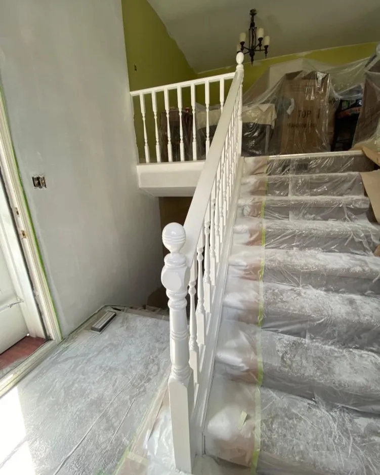 Sprayed white staircase spindles and handrail in progress, Calgary