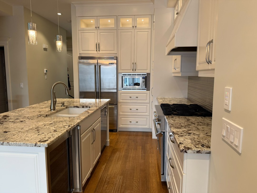 Refinished white kitchen cabinets with island and Viking fridge in Altadore, Calgary