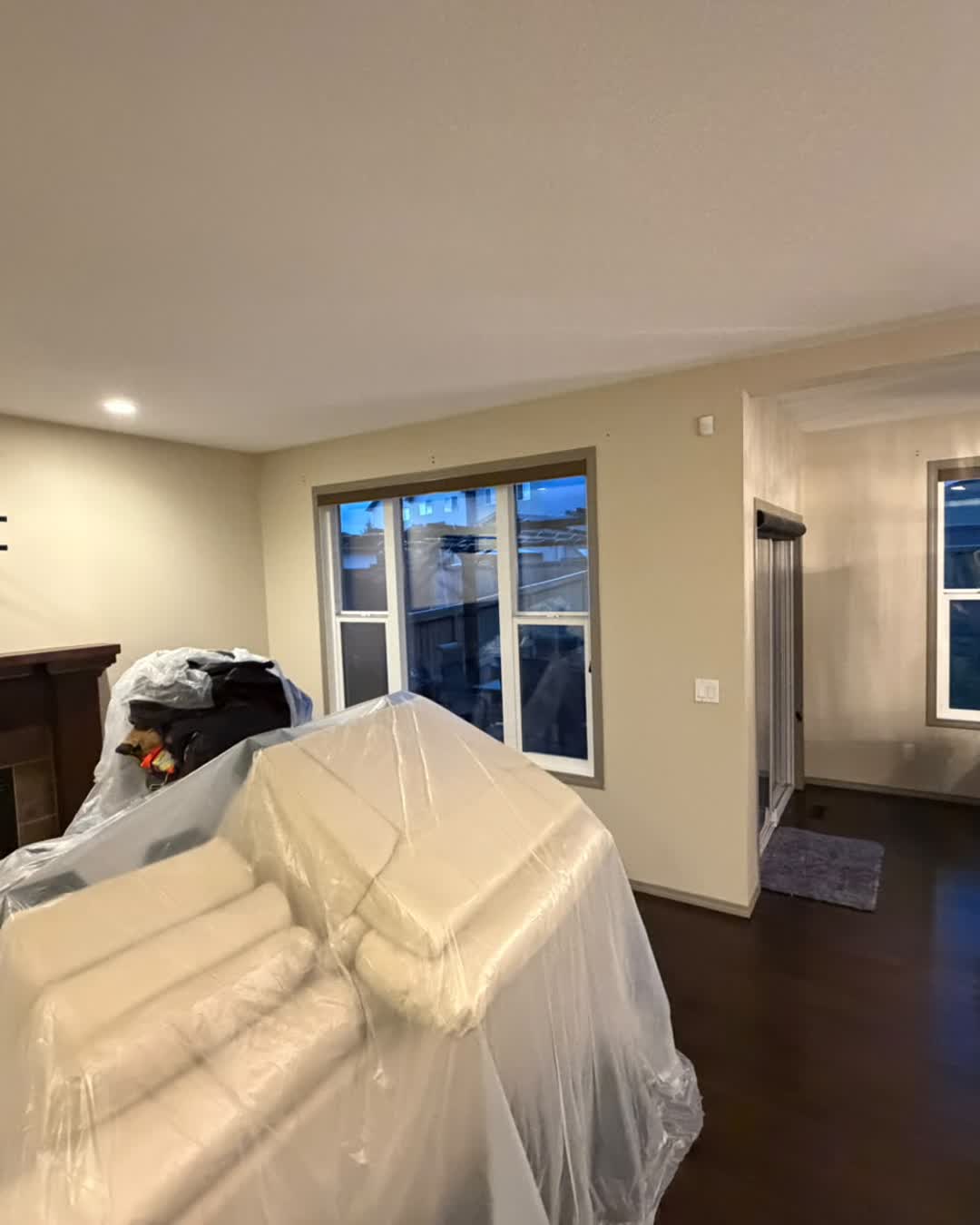 Living room with furniture wrapped and protected before painting during the Cranston interior repaint, Calgary
