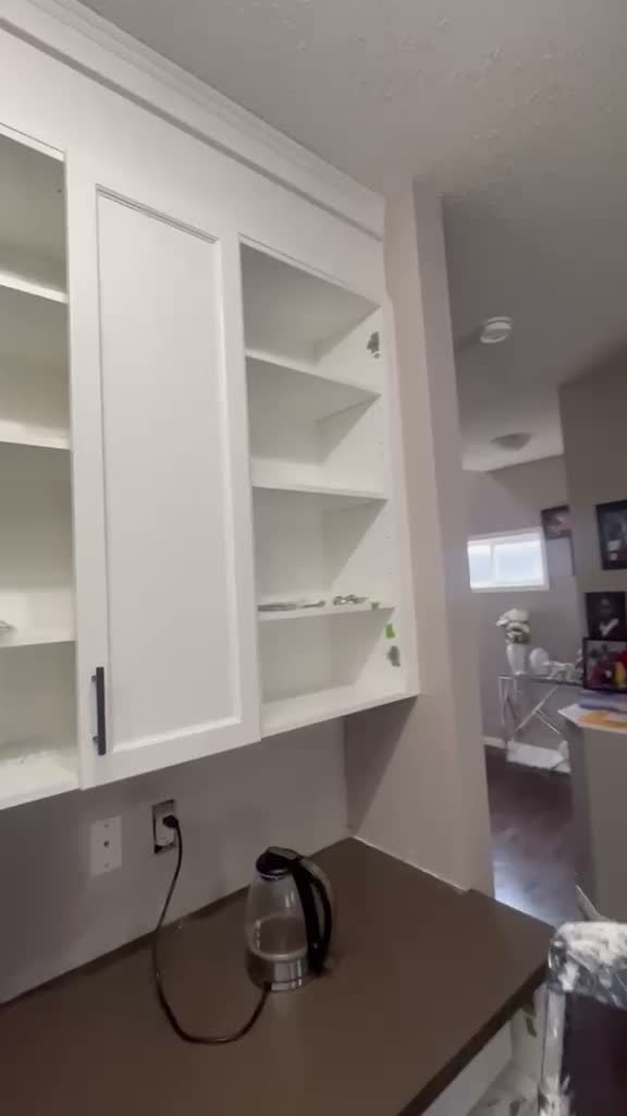Sprayed white cabinet doors being reinstalled in Kincora, Calgary