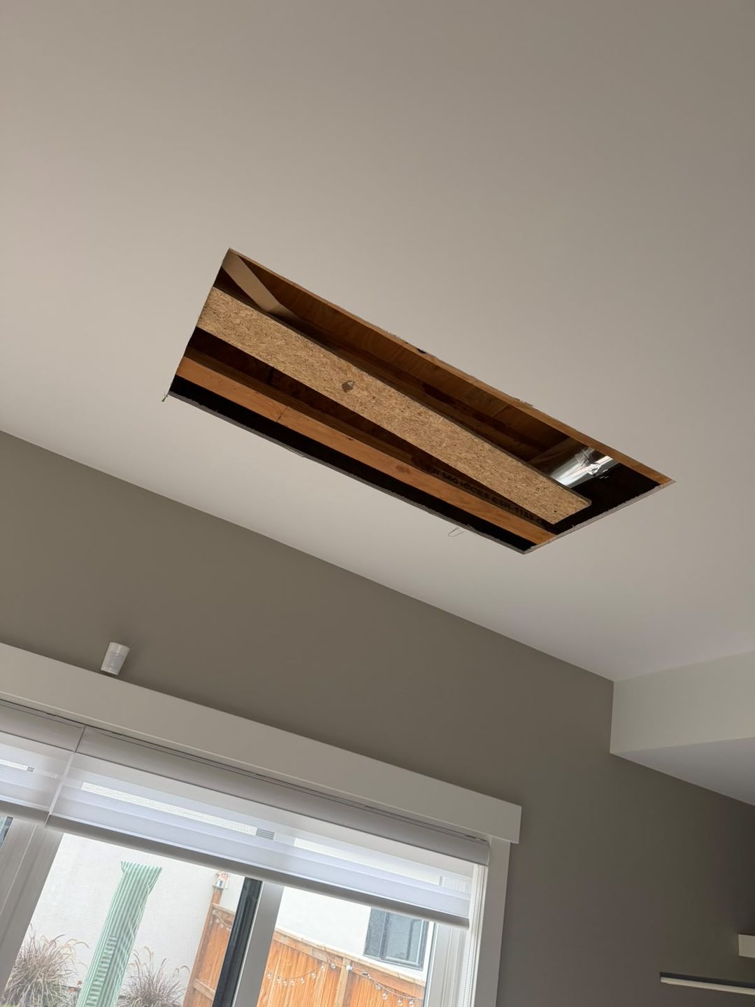 Rectangular ceiling cut-out with exposed joists after water-damaged drywall removal in Mount Pleasant, Calgary