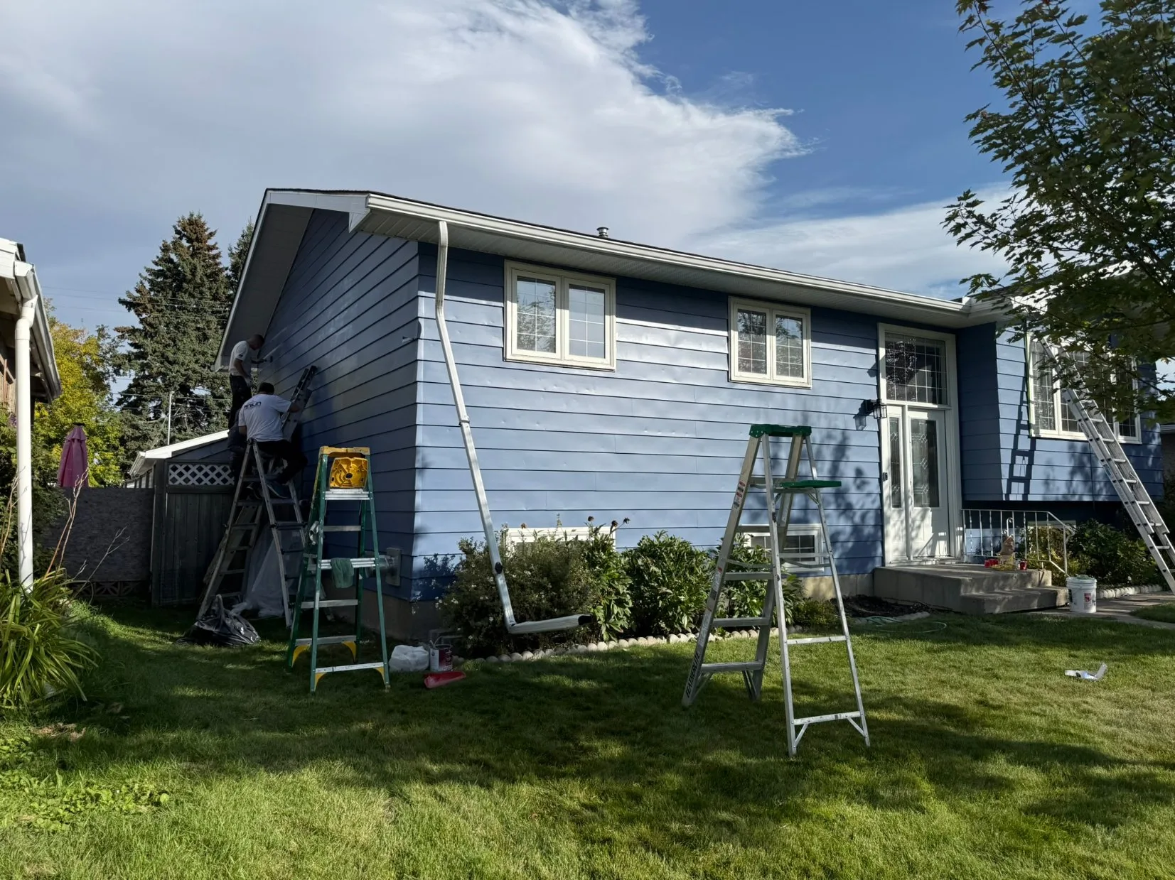 MV Painting crew painting blue house siding in Calgary