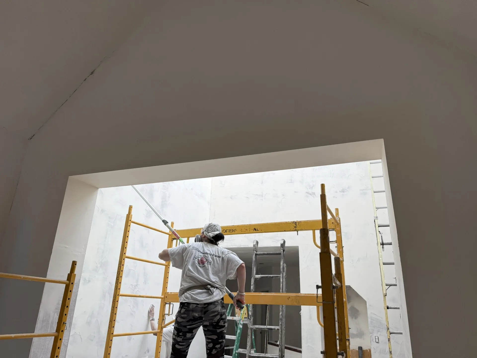 Painter spray-painting a high ceiling in Calgary